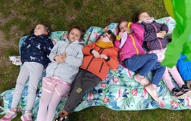 Przedszkolaki leżące w ogrodzie przedszkolnym - poszukiwanie spokoju