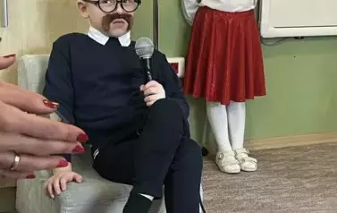 Chłopiec przebrany za dziadka siedzi na fotelu