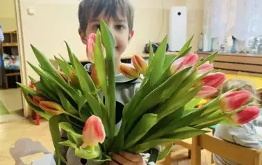 chłopiec trzyma bukiet tulipan&oacute;w