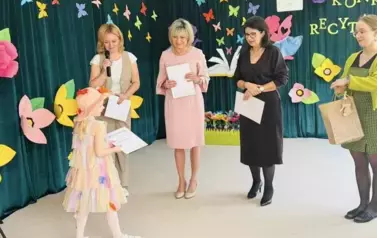Dziewczynka odbierająca wyr&oacute;żnienie od jury
