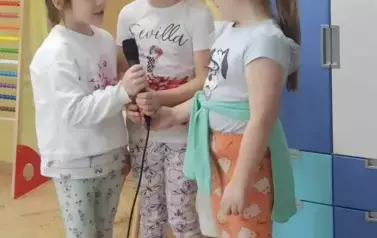 Trzy dziewczynki z grupy starszak&oacute;w śpiewają piosenkę