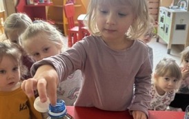 Dziewczynka wrzucająca ceiny do butelki.