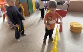 Przedszkolak wieszający pasek bibuły na sznurku.