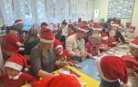 Dzieci i rodzice w czasie wykonywania papierowego anioła.