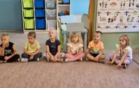 Przedszkolaki sziedzące na dywanie w czasie czytanej bajki