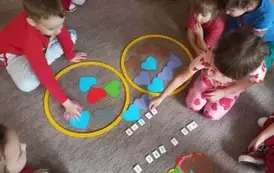 Dzieci wykonują działania matematyczne przy pomocy papierowych serduszek