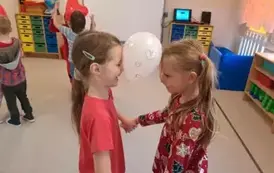 Dziewczynki tańczą z balonem pomiędzy głowami