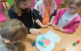Dzieci obserwują jakie wzory tworzą się z kolorowej farby wkroplonej na mleko