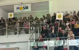 kibice na trybunach podnoszą baner z logo Mp 14